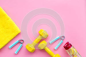 Workout with bars, bottle of water and wrist builder pink background top view mockup