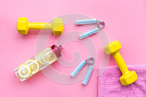 Workout with bars, bottle of water and wrist builder pink background top view mockup