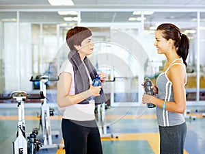 Workout buddies. Two girls talking and looking at each other in the gym.