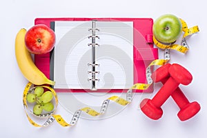 Workout and fitness dieting copy space diary. Healthy lifestyle concept. Apple, dumbbell, and measuring tape on rustic wooden