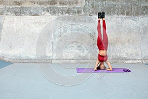 Workout. Fitness Girl Standing On Head. Sexy Woman With Raising Legs Exercises On Yoga Mat At Outdoor Stadium.