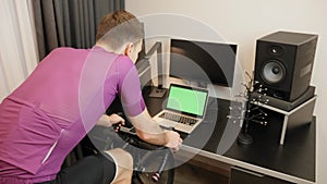 Workout at home. Male athlete is doing fitness cardio workout on exercise bicycle. Man is cycling on home stationary smart trainer