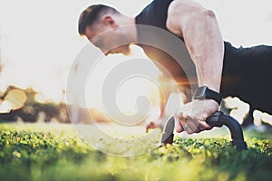 Workout lifestyle concept.Muscular athlete exercising push up outside in sunny park. Fit shirtless male fitness model in