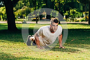 Push ups or press ups exercise by young man while working out on grass crossfit strength training