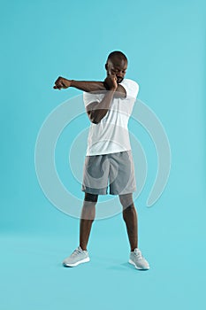 Workout. Man stretching arm, warming up on blue background