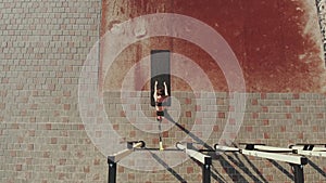workout outdoors. suspension straps. aero top view. Athletic young woman is doing all-body resistance exercises using