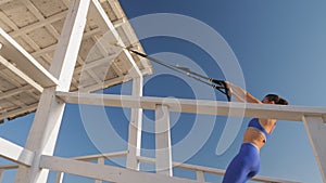 workout outdoors. suspension straps. workout with straps. Athletic young woman is doing all-body resistance exercises