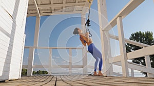 workout outdoors. suspension straps. workout with straps. Athletic young woman is doing all-body resistance exercises