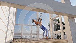 workout outdoors. suspension straps. workout with straps. Athletic young woman is doing all-body resistance exercises