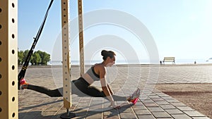 workout outdoors. suspension straps. workout with straps. Athletic young woman is doing all-body resistance exercises