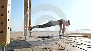 workout outdoors. suspension straps. workout with straps. Athletic young woman is doing all-body resistance exercises