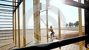 workout outdoors. suspension straps. workout with straps. Athletic young woman is doing all-body resistance exercises