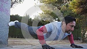 Workout with personal trainer outdoors. Fitness man doing raised leg push-ups in a park as part of a workout routine.