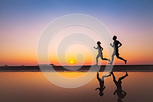 Workout, silhouettes of two runners on the beach