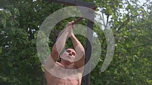 Workout training on the horizontal bar, a man doing pull-ups, training in the fresh air