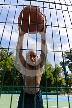 Workout. Young strong man, male basketball player training at street public stadium, sport court or palyground outdoors