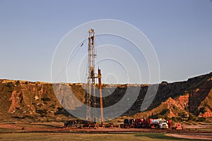 Workover rig working on a previously drilled well trying to restore production through repair in Western Oklahoma with sunset refl