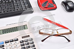 Workplace of accountant: invoice, keyboard, calculator, mouse, hole punch, glasses and red pen