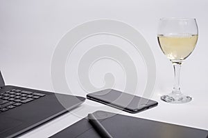 Workplace with black laptop computer, digital graphic tablet and pen smart phone and glass white wine on white background