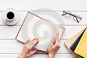 Workplace with book in hands for reading, glasses, coffee on white wooden background flatlay