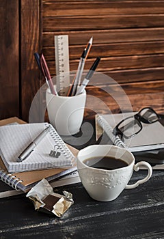 Workplace with business objects - books, notebooks, pens, tablet, glasses and a cup of coffee and chocolate.