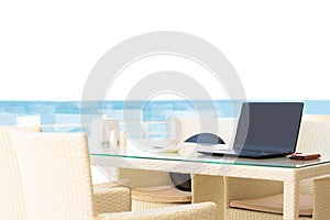 Workplace in a cafe with a sea view. Man working on a laptop in a cafe. Copy space. Mock up