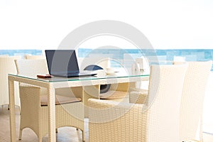 Workplace in a cafe with a sea view. Man working on a laptop in a cafe. Copy space. Mock up