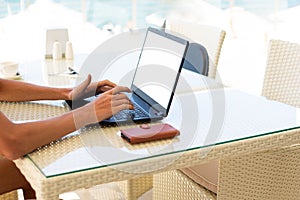 Workplace in a cafe with a sea view. Man working on a laptop in a cafe. Copy space. Mock up