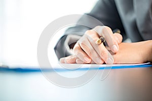 Workplace closeup person professional businesswoman sitting at desk hold pen signing or signature contract paper. Employee woman