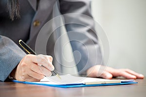 Workplace closeup person professional businesswoman sitting at desk hold pen signing or signature contract paper. Employee woman