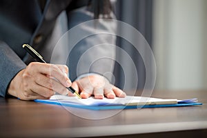 Workplace closeup person professional businesswoman sitting at desk hold pen signing or signature contract paper. Employee woman