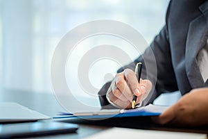 Workplace closeup person professional businesswoman sitting at desk hold pen signing or signature contract paper. Employee woman