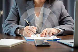 Workplace closeup person professional businesswoman sitting at desk hold pen signing or signature contract paper. Employee woman