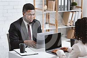 Workplace conflict. Displeased African American guy having disagreement with his female colleague at office, free space