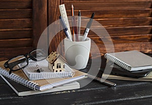Workplace designer and architect with business objects - books, notebooks, pens, pencils, rulers, tablet, glasses and a model of a