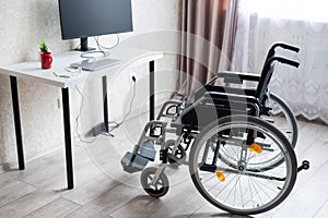 Workplace for a disabled person. Wheelchair at the table with a computer.