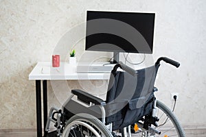 Workplace for a disabled person. Wheelchair at the table with a computer.