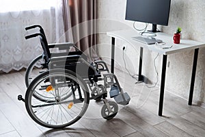 Workplace for a disabled person. Wheelchair at the table with a computer.