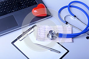 Workplace of doctor with laptop, stethoscope, red heart and RX prescription on white table. top view.