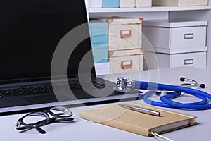 Workplace of doctor with laptop, stethoscope, RX prescription, glasses and notebook on white table. Copy space.