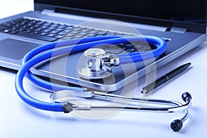 Workplace of doctor with laptop, stethoscope and RX prescription on white table. top view.