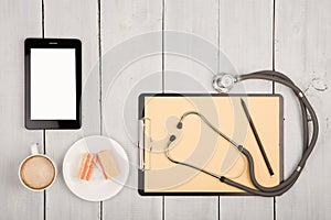 workplace of doctor - stethoscope, clipboard, tablet pc, cup of