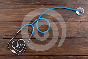 Workplace of a doctor. Stethoscope and little heart on wooden desk background