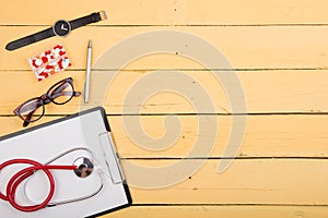 Workplace of doctor - stethoscope and other supplies on the yellow wooden desk