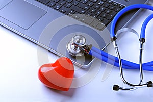 Workplace of doctor with stethoscope, red heart, laptop, rx prescription and notebook on white table. top view.