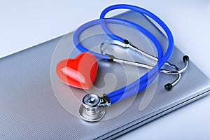 Workplace of doctor with stethoscope, red heart, laptop, rx prescription and notebook on white table. top view.