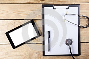 Workplace of a doctor. Tablet, stethoscope, black pen on wooden desk background. Top view.