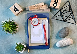 Workplace flat lay with empty notebook page, clock, flowers, stones and other scandinavian decor.