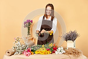 Workplace floral decor. Retail flower shop. Fresh floral arrangements. Smiling satisfied brown haired woman florist working at her