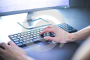 Workplace of a freelancer with computer, keyboard and typing hands